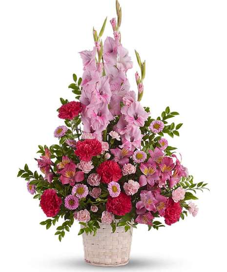 Angelic pink blooms in a white wicker basket create a beautiful sympathy arrangement for the funeral service